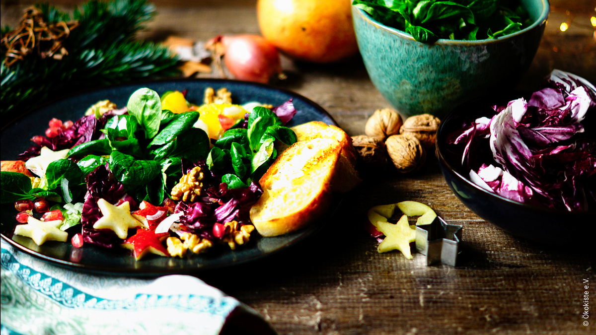 KI generiert: Das Bild zeigt eine Auswahl an Wurzelgemüsen, darunter lila Karotten, Pastinaken und eine Steckrübe, auf einem Holztisch arrangiert.