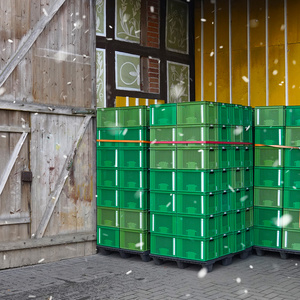 KI generiert: Das Bild zeigt einen Stapel aus grünen Kunststoffkisten vor einer Scheuneneinfahrt, die mit bemalten Paneelen dekoriert ist. Es schneit leicht im Vordergrund.