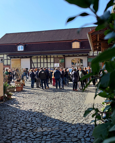 KI generiert: Eine Menschenmenge versammelt sich auf einem gepflasterten Hof vor einem Fachwerkhaus.