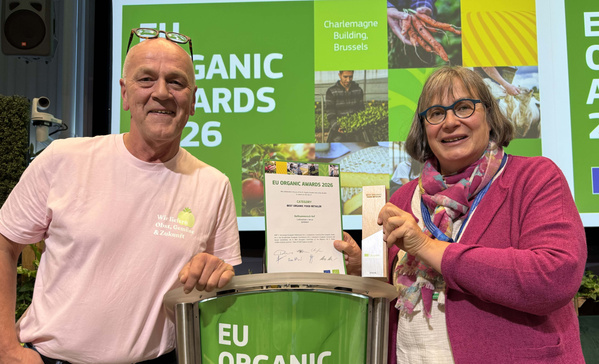 KI-generierte Beschreibung: Zwei Personen halten Urkunden bei den EU Organic Awards 2021.