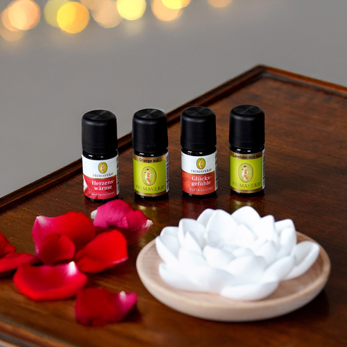 KI generiert: Vier Fläschchen mit ätherischen Ölen, daneben Roséblätter und eine weiße Blume.