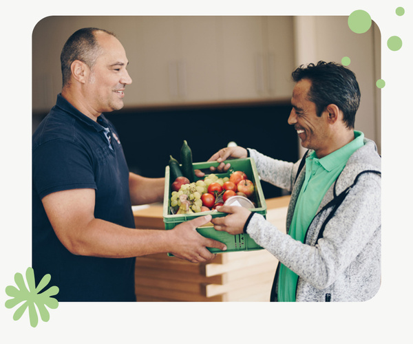 Mann übergibt Kiste mit Obst & Gemüse