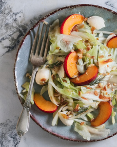 Das Bild zeigt mehrere Personen, die in einer Küche zusammenarbeiten, vermutlich bei einem Kochkurs oder einer Gruppenkochaktivität. Sie tragen Schürzen und sind mit der Zubereitung von Zutaten beschäftigt.