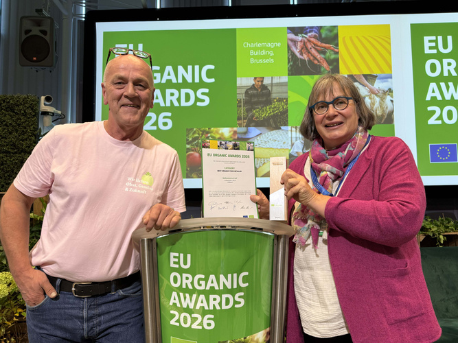 KI-generierte Beschreibung: Zwei Personen halten Urkunden bei den EU Organic Awards 2026.