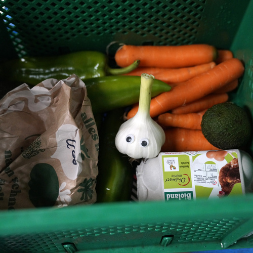 Gepackte Obst- und Gemüsekiste mit frischem Knoblauch mit Wackelaugen