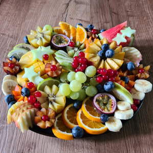 Das Bild zeigt mehrere Personen, die in einer Küche zusammenarbeiten, vermutlich bei einem Kochkurs oder einer Gruppenkochaktivität. Sie tragen Schürzen und sind mit der Zubereitung von Zutaten beschäftigt.