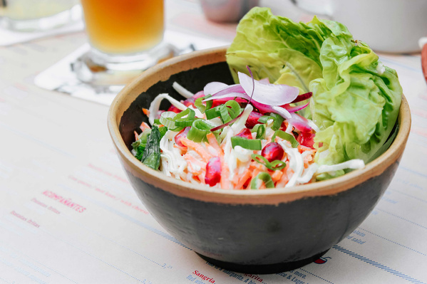 KI generiert: Das Bild zeigt zwei Hähnchenspieße, die auf einem Salatbett in einer rosa Schale liegen. Daneben befinden sich zwei Schälchen mit verschiedenen Saucen.