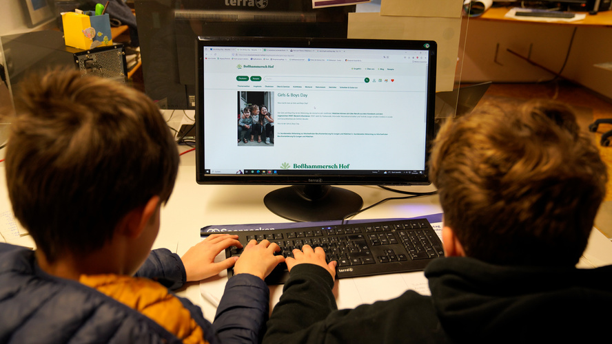 Zwei Jungs sitzen am Computer und erstellen eine Webseite