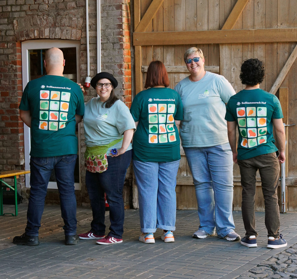 KI generiert: Fünf Personen stehen zusammen, tragen T-Shirts des "Bohlsener Hofs".