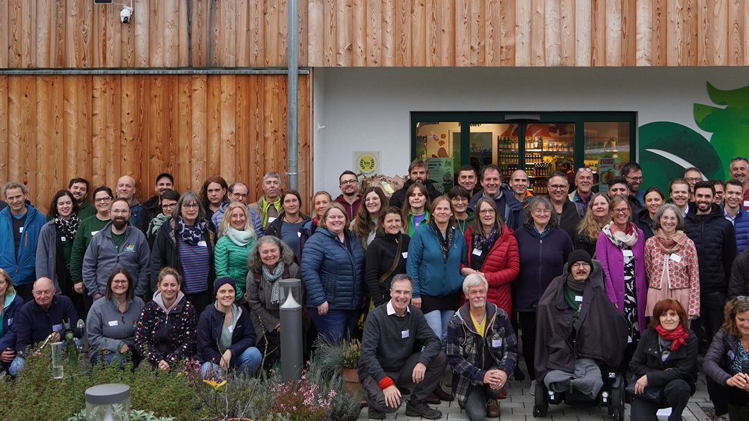 KI generiert: Auf dem Bild steht ein lächelnder Mann mit frisch geerntetem Gemüse auf einem Feld neben einem Traktor. Die Szene findet unter klarem Himmel und in ländlicher Umgebung statt.
