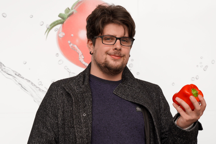 Praktikant Lasse mit einer roten Paprika in der Hand