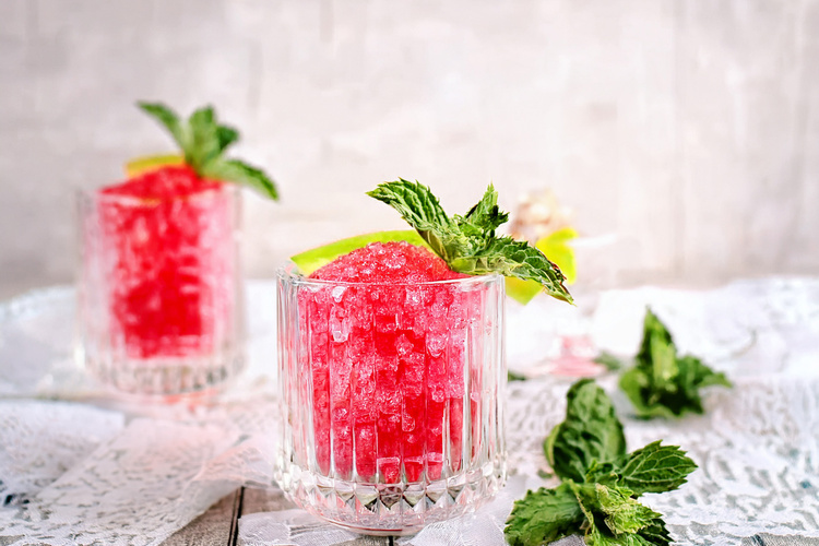 KI generiert: Zwei Gläser mit rotem Crushed Ice, Minzblättern und Limettenscheiben.