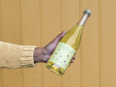 KI generiert: Das Bild zeigt eine Weinflasche mit der Aufschrift "Schönhals Samt & Seide" auf einer hölzernen Treppe, die von einem grauen Stoff umgeben ist. Der Fokus liegt auf der Weinflasche.