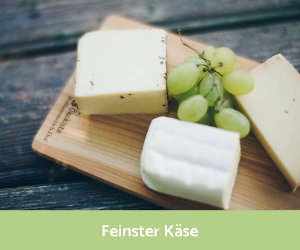 verschiedene Käsesorten auf einem Holzbrett mit Weintrauben dekoriert