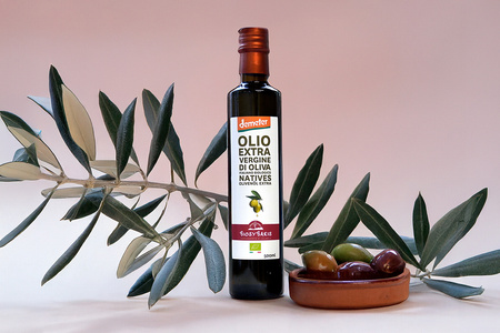 KI generiert: Das Bild zeigt eine Weinflasche mit der Aufschrift "Schönhals Samt & Seide" auf einer hölzernen Treppe, die von einem grauen Stoff umgeben ist. Der Fokus liegt auf der Weinflasche.