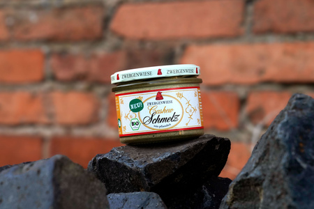 KI generiert: Das Bild zeigt eine Weinflasche mit der Aufschrift "Schönhals Samt & Seide" auf einer hölzernen Treppe, die von einem grauen Stoff umgeben ist. Der Fokus liegt auf der Weinflasche.