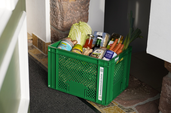 KI generiert: Eine grüne Kiste mit frischen Lebensmitteln steht vor einer Haustür.

Text: koshinaunser-biok...