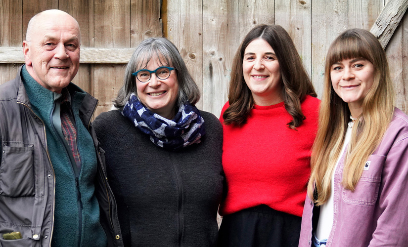 KI generiert: Eine Gruppe von vier lächelnden Personen vor einer Holzwand.