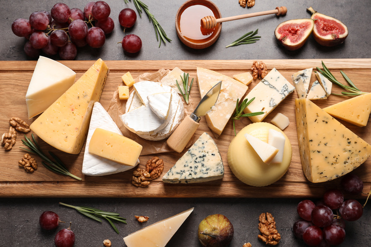 Holzbrett mit vielerlei Käse, dazu Weintrauben, Walnüsse und Feigen
