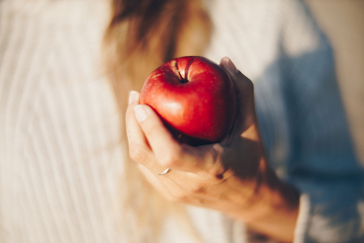 Frau hält Apfel in der Hand