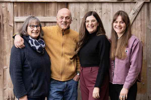 KI generiert: Eine Gruppe von vier Personen steht lächelnd vor einer Holzwand.