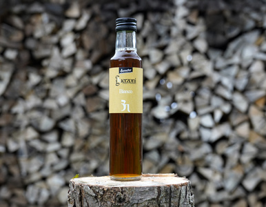 KI generiert: Das Bild zeigt eine Weinflasche mit der Aufschrift "Schönhals Samt & Seide" auf einer hölzernen Treppe, die von einem grauen Stoff umgeben ist. Der Fokus liegt auf der Weinflasche.