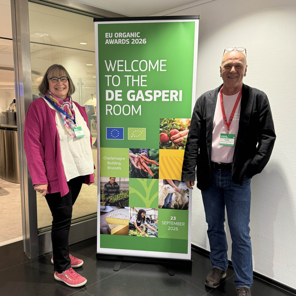KI-generierte Beschreibung: Zwei Personen vor einer Begrüßungstafel für den "De Gasperi Room". Text: "EU ORGANIC AWARDS 2026 WELCOME TO THE DE GASPERI ROOM".
