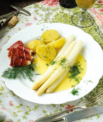 KI generiert: Ein Teller mit weißem Spargel, Kartoffeln, Schinken und Buttersoße, garniert mit Dill.
