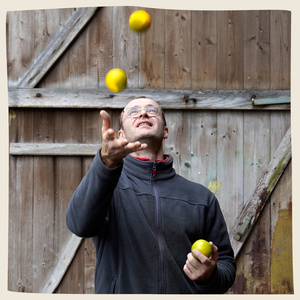 KI generiert: Eine Person jongliert mit gelben Bällen vor einem hölzernen Hintergrund. Der Fokus liegt auf der Jonglieraktion.