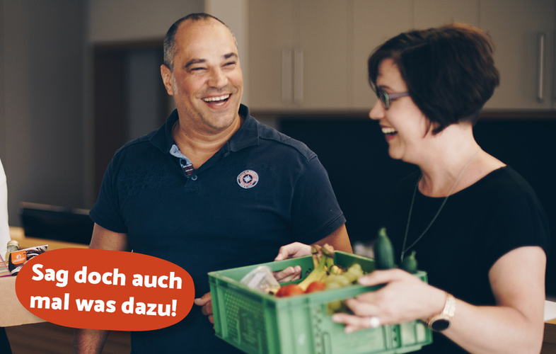 Daniela hält lachend eine Obst- und Gemüsekiste in der Hand