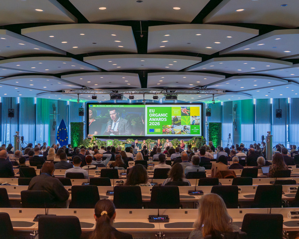 KI-generierte Beschreibung: Hauptinhalt: Publikum bei einer Konferenz oder einem Event. Text: "EU Organic Awards 2026".