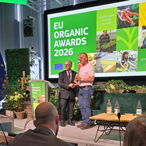 KI-generierte Beschreibung: Zwei Personen vor einem EU Organic Awards 2026 Banner.