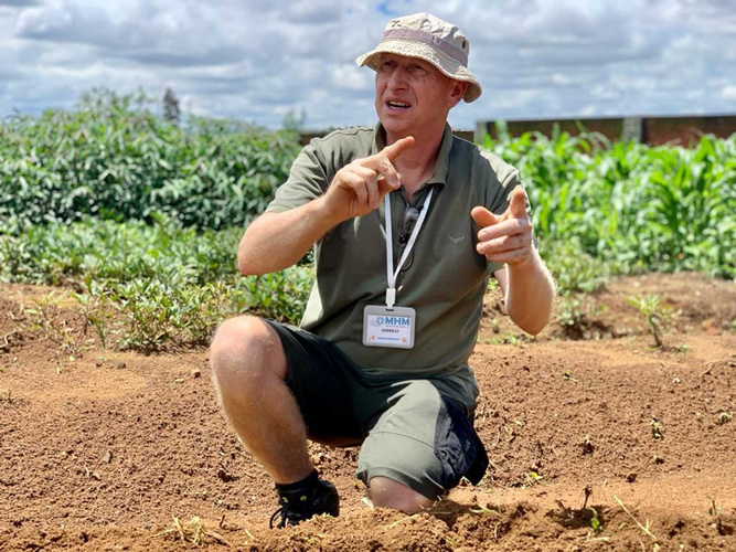 Andreas Hanisch kniet im Acker in Madagaskar und erzählt