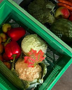 Das Bild zeigt mehrere Personen, die in einer Küche zusammenarbeiten, vermutlich bei einem Kochkurs oder einer Gruppenkochaktivität. Sie tragen Schürzen und sind mit der Zubereitung von Zutaten beschäftigt.