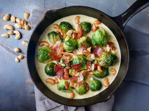 KI generiert: Rosenkohl in einer Pfanne mit Speck, Cashewkernen und cremiger Sauce.