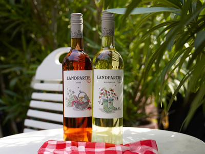 Das Bild zeigt mehrere Personen, die in einer Küche zusammenarbeiten, vermutlich bei einem Kochkurs oder einer Gruppenkochaktivität. Sie tragen Schürzen und sind mit der Zubereitung von Zutaten beschäftigt.