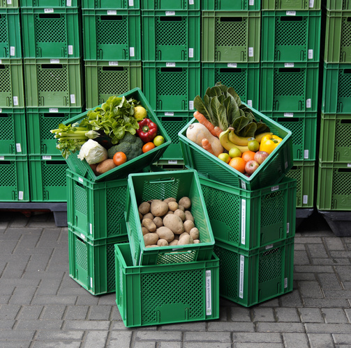 KI generiert: Grüne Kisten mit frischem Obst und Gemüse, gestapelt auf dem Boden.