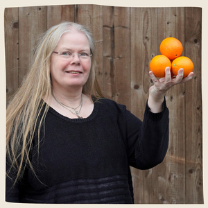 KI generiert: Das Bild zeigt eine Person vor einem Holzhintergrund, die lächelnd drei Orangen in der Hand hält. Der Hauptinhalt des Bildes ist die Darstellung der Orangen als besonderes Element.