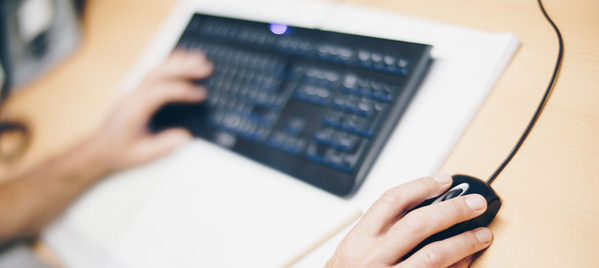 KI generiert: Eine Person benutzt Maus und Tastatur auf einem Schreibtisch.