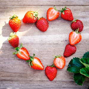 Das Bild zeigt mehrere Personen, die in einer Küche zusammenarbeiten, vermutlich bei einem Kochkurs oder einer Gruppenkochaktivität. Sie tragen Schürzen und sind mit der Zubereitung von Zutaten beschäftigt.