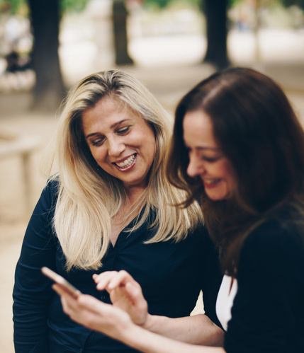 Zwei Frauen lachen und schauen aufs Handy