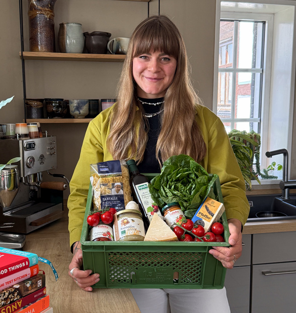 KI generiert: Zwei Personen stehen in einem Gewächshaus voller Pflanzen und halten eine Kiste mit frischem Gemüse. Der Fokus liegt auf der Präsentation der Ernte.