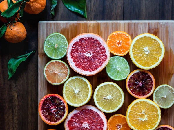 KI generiert: Verschiedene aufgeschnittene Zitrusfrüchte auf einem Holzbrett, lebhaft und bunt arrangiert.